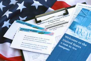 Permanent resident green card in envelope with application and guide for new immigrants lies on US...