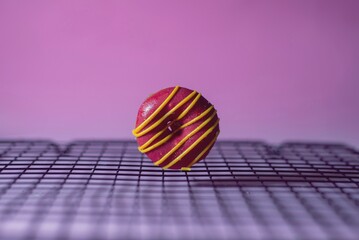 Close-up de dona rosa  glaseada en amarillo sobre rejilla