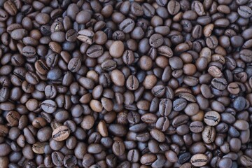 Roasted coffee beans background in warm dark scene close up