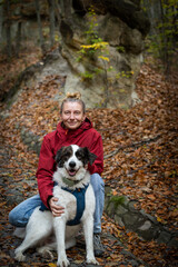 happy white dog with owner in autumn forest