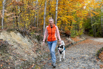 Fototapeta premium happy white dog with owner in autumn forest
