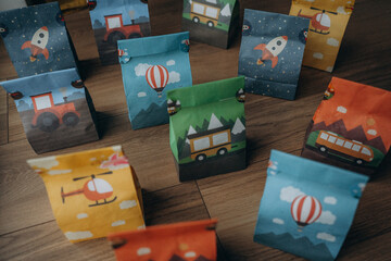 Obraz premium Small gift bags for guests at a child's birthday party. Multi-colored gift bags with transport: a hot air balloon, a rocket, a bus, a helicopter, a tractor