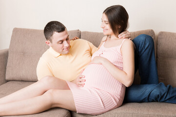Happy pregnant woman and her husband waiting for baby at the home. happy family love and care concept