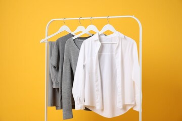 Obraz premium Different clothes hanging on rack against orange background
