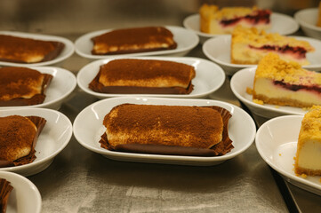 Assorted tiramisu and cheesecake slices on plates in a bakery setting
