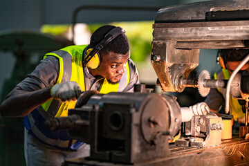 Focused industrial technician operating heavy machinery with precision. Wearing ear protection and...