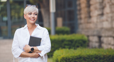 Smiling adult woman posing and holding book. Cheerful pretty adult woman with a book