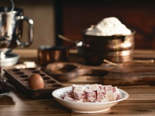 Lokum, also known as Turkish Delight, sits in a white bowl with flour, eggs, chocolate, and antique kitchenware ready for a baking project in an old Istanbul kitchen