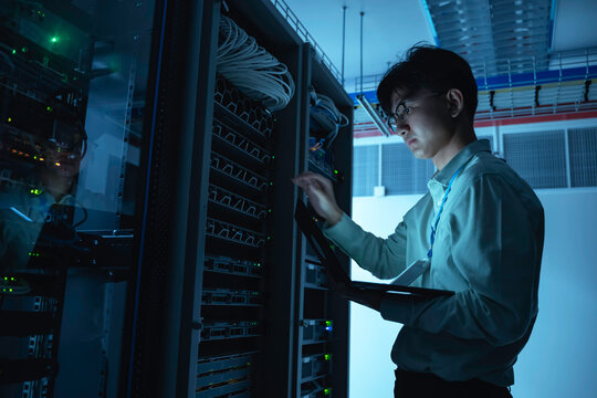 Computer engineer is setting up network in server room,Systems Maintenance Technician,Male engineer working in server room at modern data center