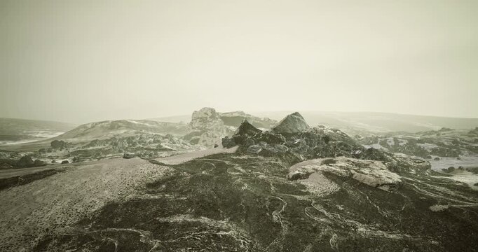 Rugged terrain features unique rock formations under an overcast sky. The scene captures a sense of isolation and tranquility in a cold, desolate environment, showcasing natures raw beauty.