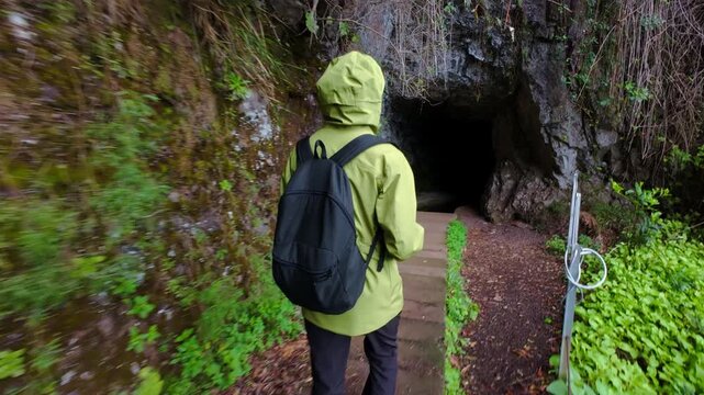 Woman walking on hiking trail to cave tunnel Levada in Madeira Island, handheld shot