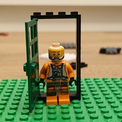 Naklejka premium LEGO® minifigure in a doorway constructed from LEGO® bricks, with green baseplate, indoors, daytime