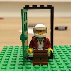Naklejka premium Lego Ferrari Minifigure Stands in Doorway on Green Base Plate
