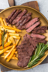 BBQ Grilled Beef Skirt Machete Steak on a plate with french fries grey background. top view