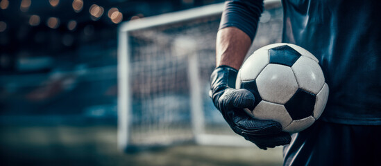 Athlete stands with soccer ball in front of goal during an evening practice session