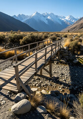 Small Wooden Bridge Over Dry Riverbed with Distant Snow-Capped Mountain