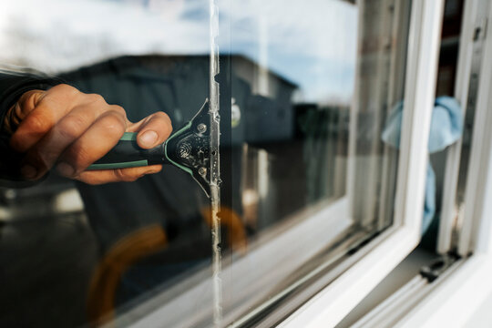 Professional window cleaning with squeegee and microfiber cloth on residential building