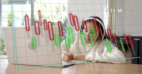 Teen taking notes from laptop as chart overlay fluctuating prompts faster finance notes - Powered by Adobe