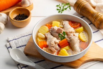 Chicken Potato Soup,Potatoes Soup With Chicken wing(drumettes) carrot tomato and onion in white bowl.Clear soup.