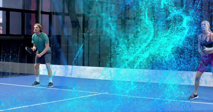 Man serving ball on blue court, woman readying, initiating teal particles highlighting fitness