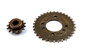 A close-up of a dirty, oily sprocket set against a white background. The image reflects maintenance.