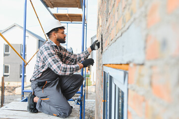Construction worker plastering brick wall on scaffolding
