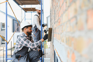 Construction workers plastering exterior wall of building facade