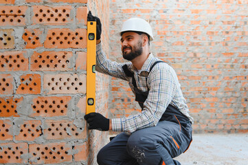 Construction worker using level tool checking brick wall