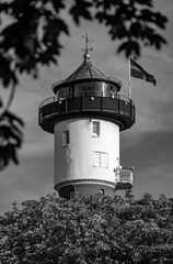 The historic lighthouse with its red and white façade on the North Sea island of Wangerooge is a landmark, tourist attraction, and popular public monument. Black and white vintage in idyllic park.