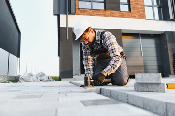 Construction worker paving driveway with concrete blocks