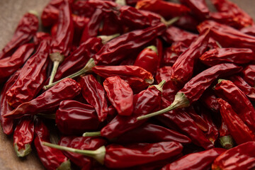 Pile of red chili peppers in a wooden bowl, 45-degree angle view filling the frame