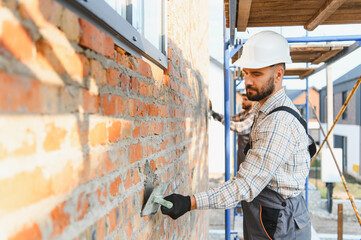 Construction worker laying brick wall with trowel
