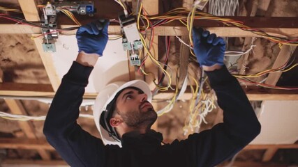 Electrician installing electrical wiring in ceiling structure of building. Professional technician working on power cables, home renovation and construction service, interior infrastructure setup, ski
