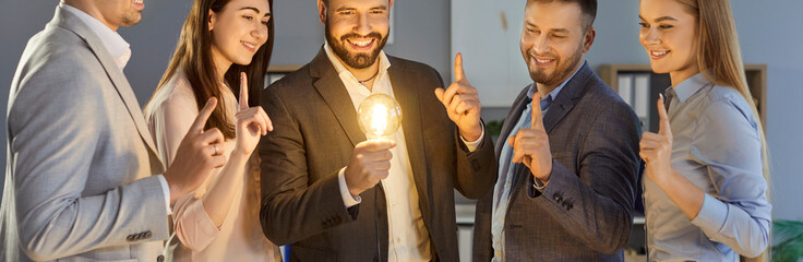 Group of a happy creative smiling business people men and women standing in a row in office holding...