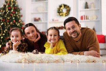 Happy family on floor in room decorated for Christmas