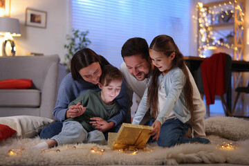 Happy family with open magic Christmas gift on floor in festive decorated room