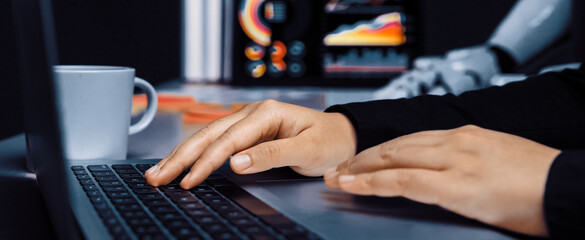 A person is typing on a laptop in a sleek office setting, with data visualizations on screen and a coffee cup nearby, showcasing a modern work atmosphere.Noogenesis