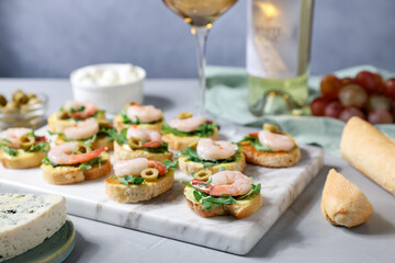 Delicious bruschettas with shrimps on light table, closeup