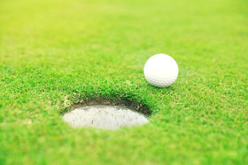 Golf ball near hole on green course outdoors