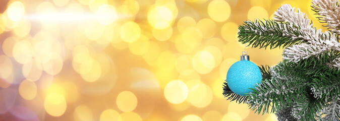 Christmas tree branches with blue balls against blurred lights, bokeh effect. Banner design with space for text