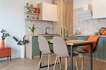 Dining room with table and chairs. Interior of kitchen with green furniture, wooden floor and elegant design. New home. Nobody.