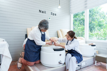 Senior Asian mother assisting young daughter preparing spa equipment for grand opening of new small...