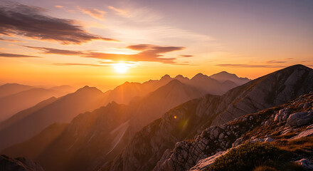 Golden sunset illuminating mountain range with visible rocks and layered peaks in the distance