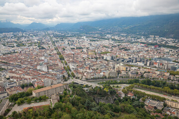 Fototapeta premium Aerial view of Grenoble old town seen from Bastille Fort, Auvergne-Rhone-Alpes region, France, Europe. View from above on the Isere Valley in the French Pre-Alps. Chartreuse Belledonne mountain range