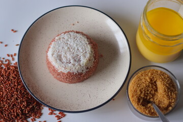 Navara rice puttu, steamed rice cake served along a glass jar of ghee and a bowl of jaggery powder