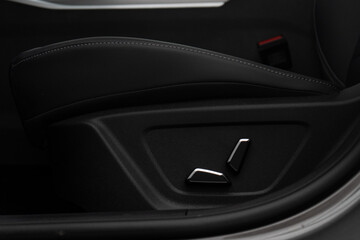 Driver's seat, view of electric buttons lever system to level and move it to a different position. Close-up Interior view with electric seat adjustment, buttons of luxury very expensive new black car	