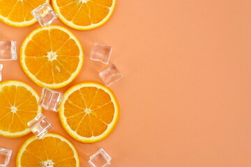 Sliced ​​oranges with ice cubes lie on a pink background.