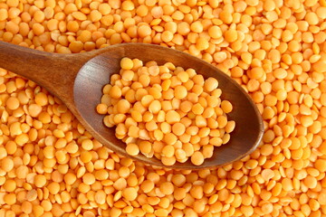 Yellow lentil texture with wooden spoon.