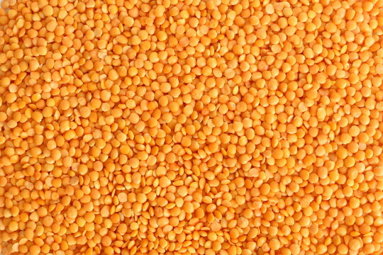 Texture of yellow lentils scattered on the surface.
