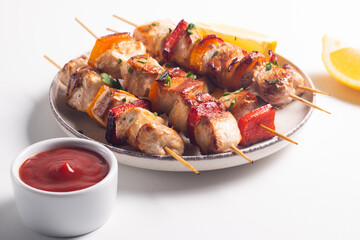 Delicious grilled chicken skewers with capsicum, lemon, salad and ketchup on a plate over the table. Chicken kebab. Healthy food concept.